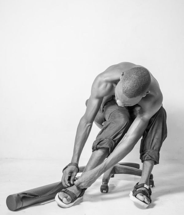 Focused man holding a challenging balance pose in a minimalist studio.